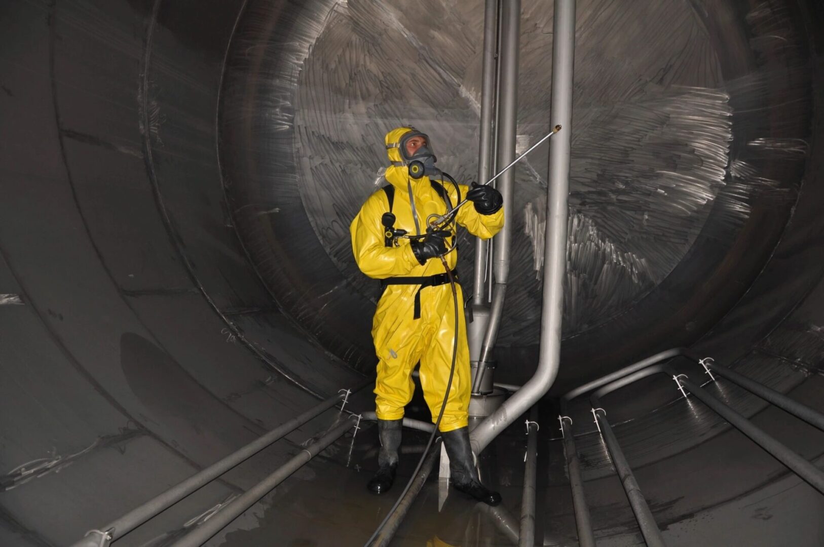 A man in yellow suit and black pants standing inside of a pipe.